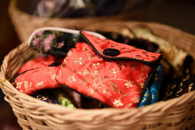 Red brocade coin purse in basket with other brocade coin purses