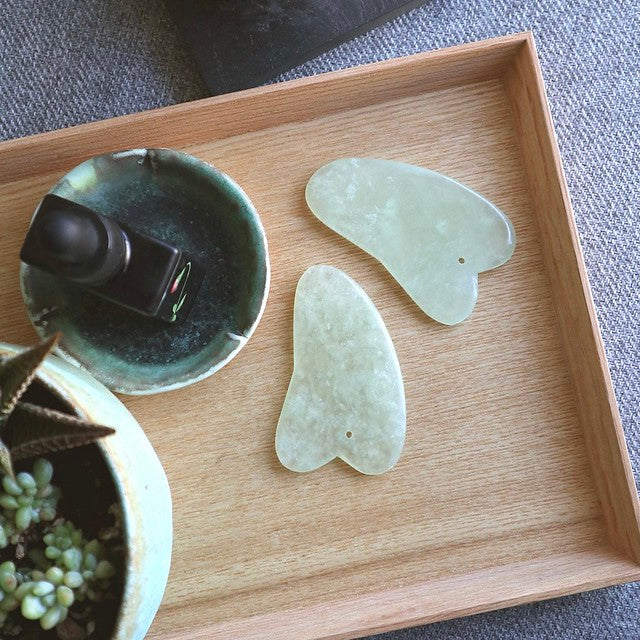 Two gua sha on wooden tray