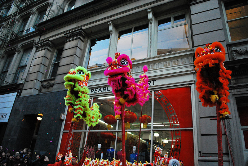 Three lion dancers on stilts in front of Pearl River Mart in Tribeca