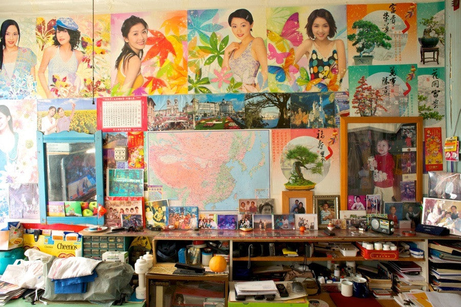 Several posters of Chinese women in front of map of China and cluttered shelf