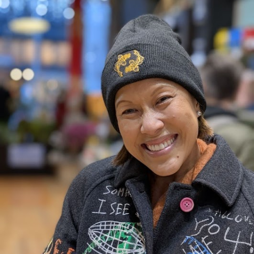 Woman with black Pearl River Mart beanie in winter coat in store