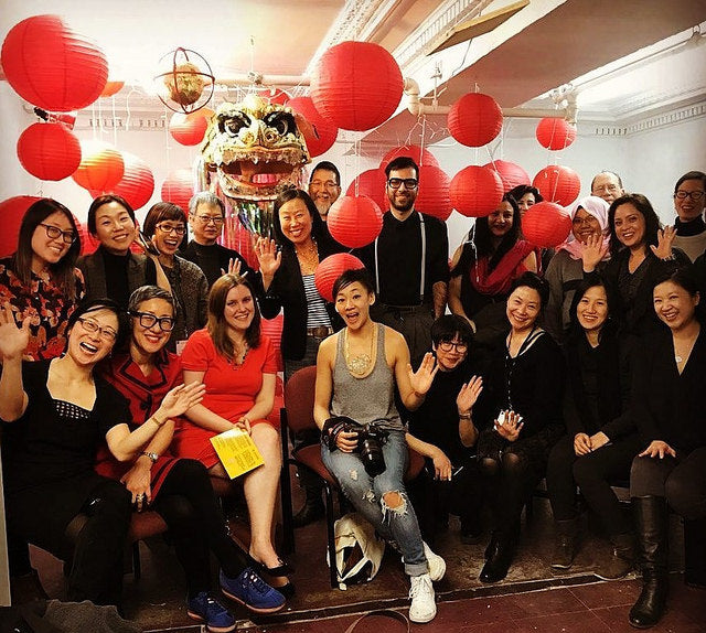 Artist Wiena Lin surrounded by friends with red lanterns and lion head art piece in background