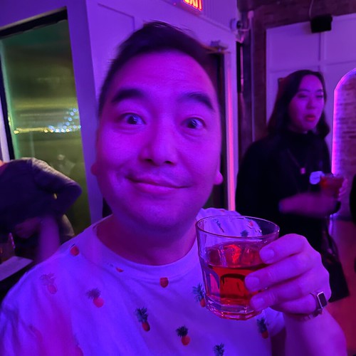 Jerry Man holding a cocktail with woman in the background
