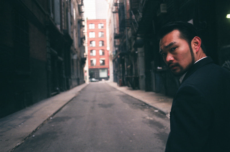 Photographer Johnny Tang looking behind him down an empty alleyway