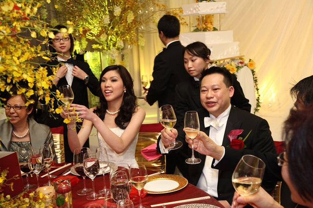 Bride and groom toast while sitting at table