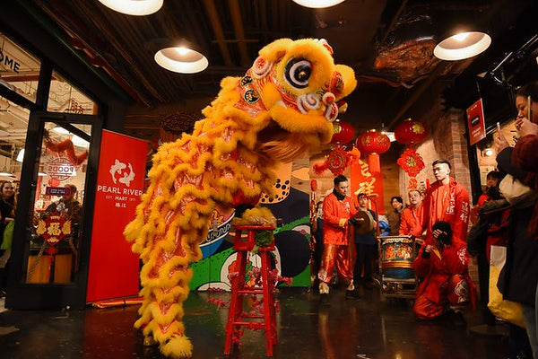 Lion dancer on stool in front of Pearl River Mart Foods