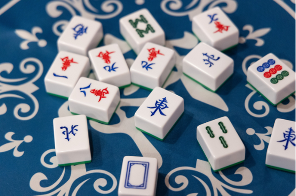 Scattering of mahjong tiles on blue mat with white design