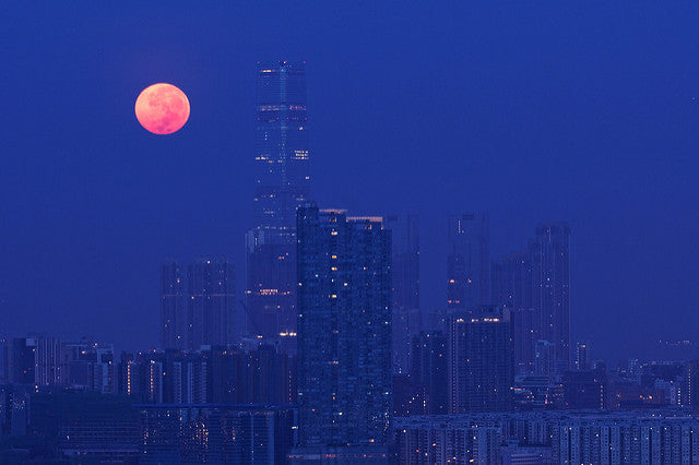 A night view of a city with a beautiful pink moon