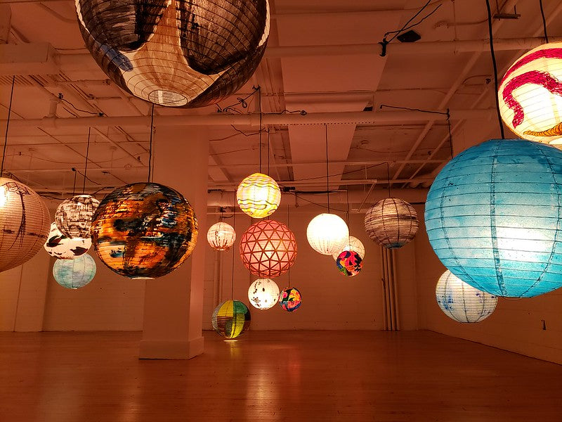 Individually painted lanterns hanging in a gallery