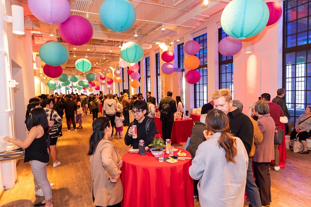 Party goers at red tables under colorful lanterns