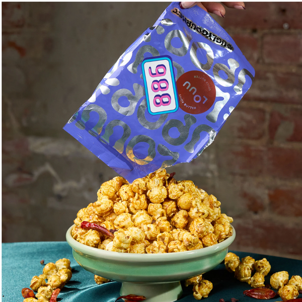 Bag of popcorn being poured into a bowl with a blue bag labeled '886' on a textured background.