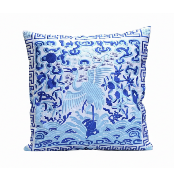 Decorative pillow with blue and white crane design on a white background