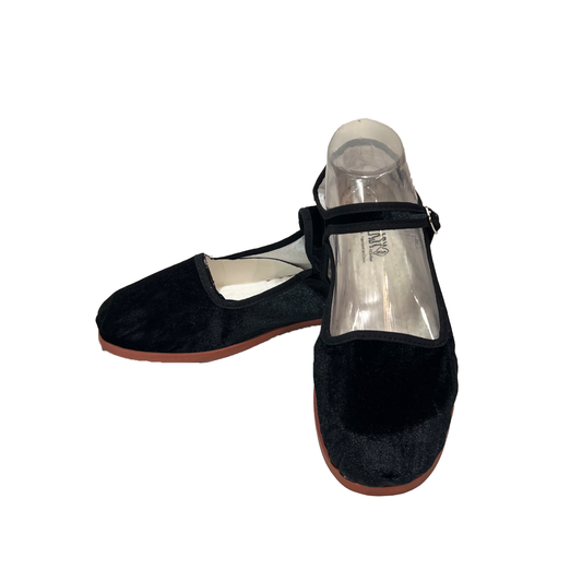 A pair of black velvet Mary Jane shoes with clear plastic inserts on the instep, displayed against a solid white background.