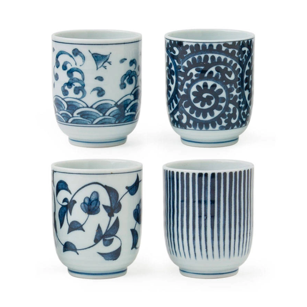 Set of four blue and white ceramic cups with various patterns on a white background