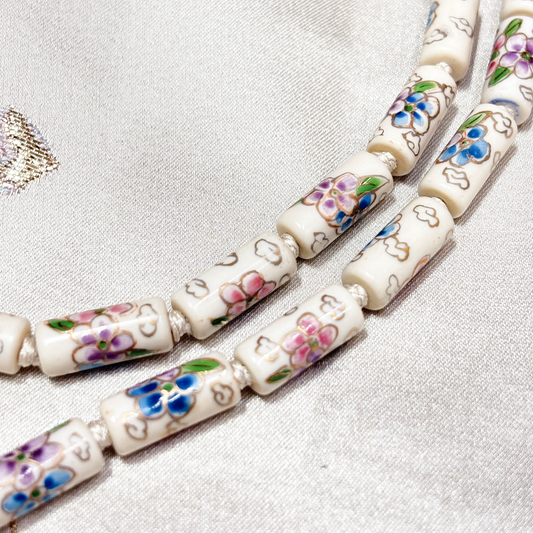 Close up of tube-shaped cloisonne design necklace - white