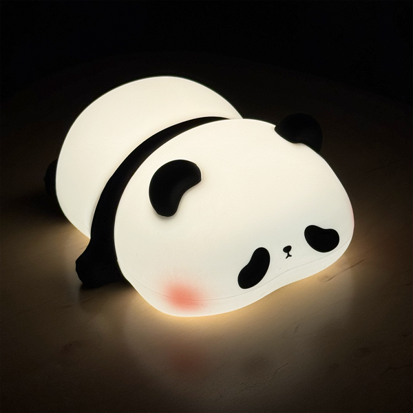 A cute panda-shaped night light glowing with warm white light, resting on a dark wooden surface against a black background.