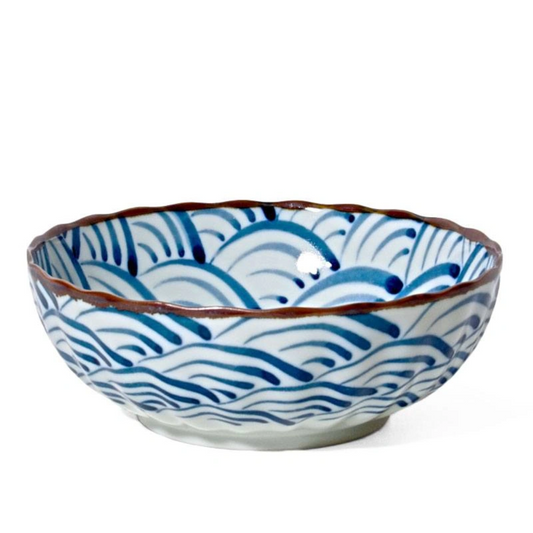 A ceramic bowl with blue wave patterns on a white base. The scalloped rim adds elegance, conveying a sense of traditional craftsmanship.