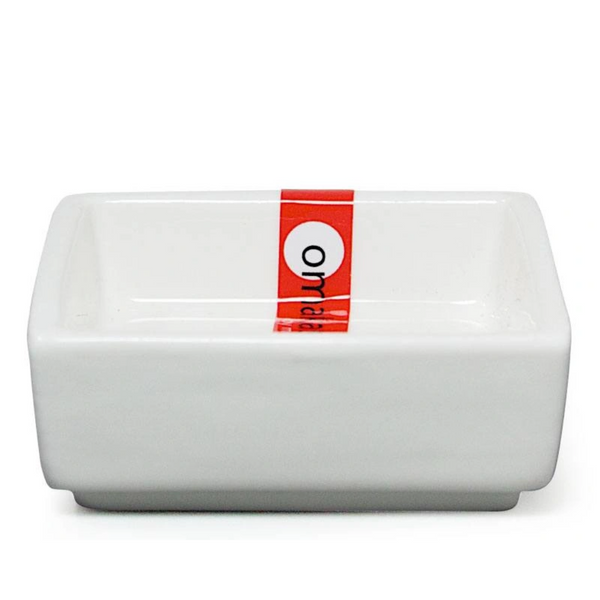 White rectangular sauce dish with a red label featuring a logo on a white background