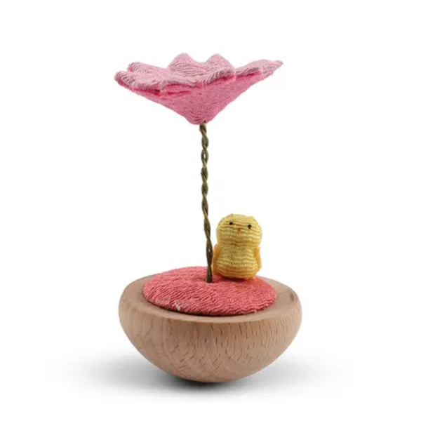 Small wooden toy with a pink flower and yellow creature on a white background