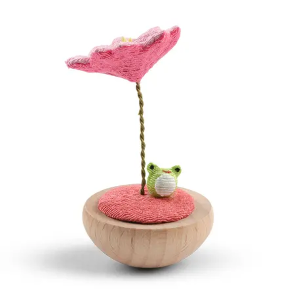 Toy with a pink flower and green frog on a white background