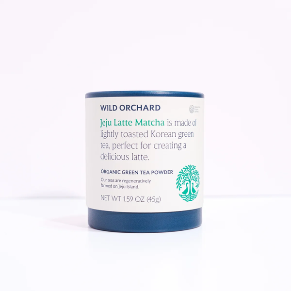 Wild Orchard Jeju Latte Matcha organic green tea powder in a cylindrical white jar with dark blue lids and base, on a white background.