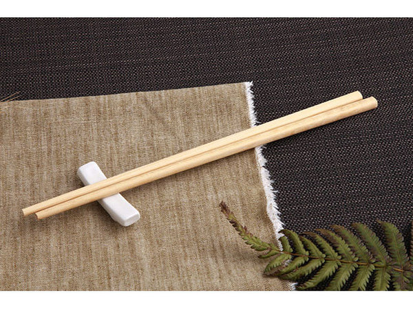Light tone wooden chopsticks- 1 pair on top of chopstick rest