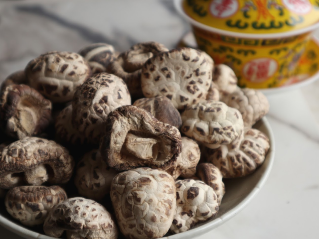 Dish of dried mushrooms with yellow tea bowl in the background