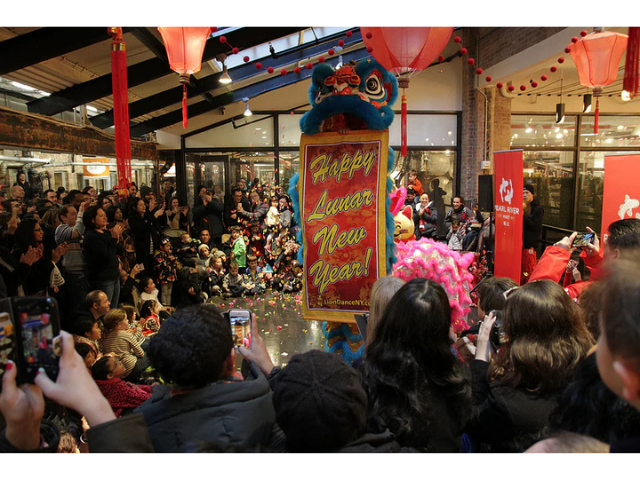 Lion dancer with happy new year banner in Chelsea Market with crowd of revelers