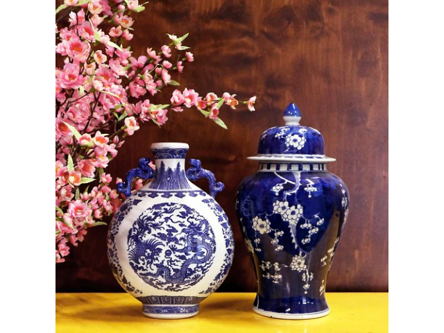 Two blue on white vases on yellow table with pink flowers