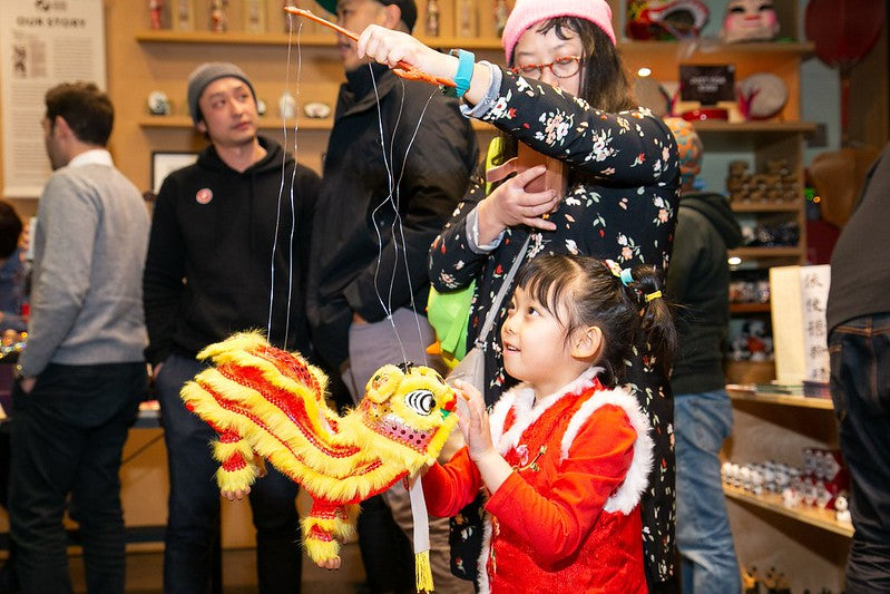 Little girl and her mother playing with a Chinese lion puppet