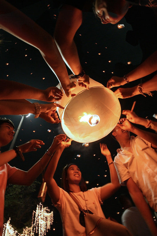 A group of young people light a floating candle in honor of the king of Thailand and, by extension, all fathers