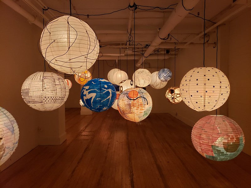 Array of individually painted lanterns in a gallery