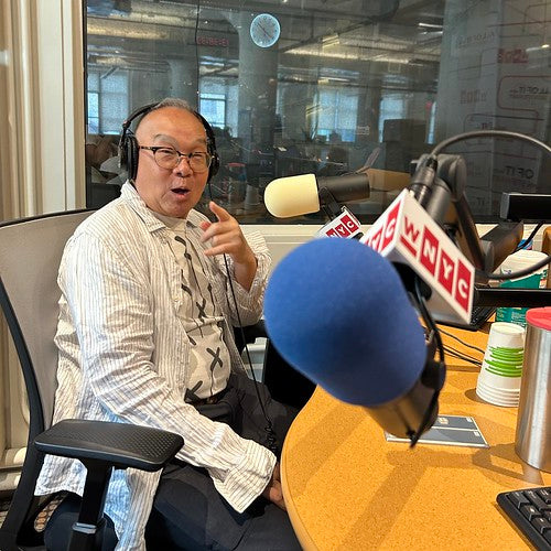 Arlan Huang in studio at WNYC with microphone in foreground