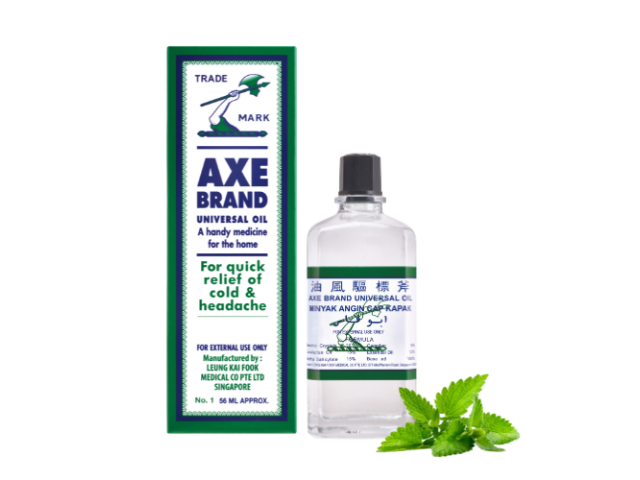 Bottle of Axe Brand pain relieving oil beside box and sprig of leaves 