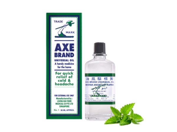 Bottle of Axe Brand pain relieving oil beside box and sprig of leaves 