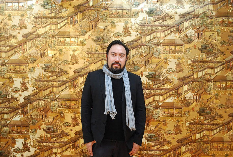 Artist Ben Sloat in front of gold wallpaper with Chinese landscape design