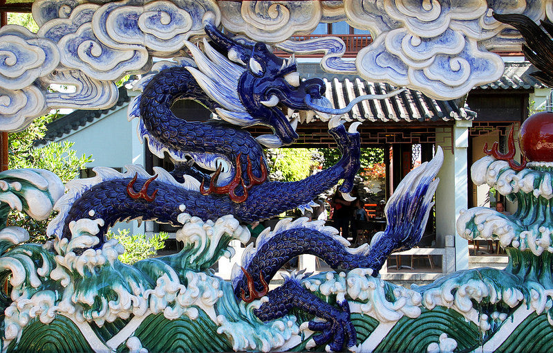 Mosaic of blue dragon in clouds and above water