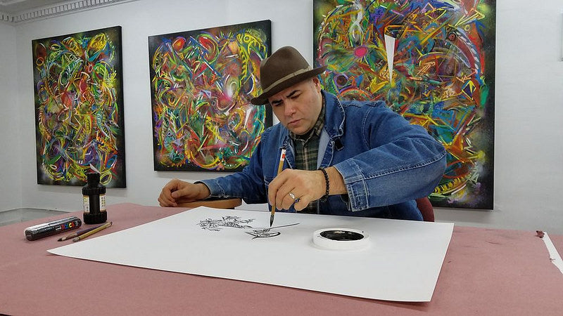 Artist Chris Mendoza painting in front of his art work in the Pearl River Mart gallery in Tribeca