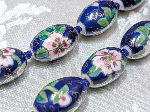 Close-up of blue porcelain oval necklace beads with pink lotus and cloisonne design