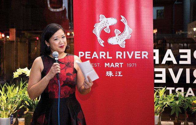 Pearl River Mart President Joanne Kwong speaking at store opening in front of Pearl River Mart red banner