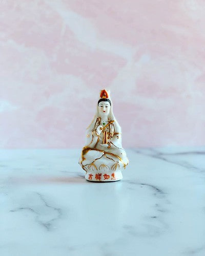 Peaceful white figurine of Guan Yin against a bright background