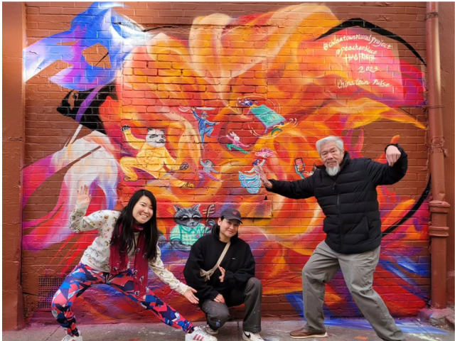 Karlin Chan in front of Chinatown mural with artists Peach Tao and Thao