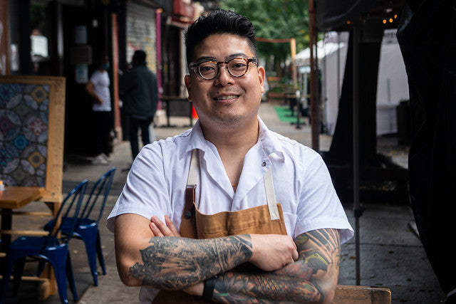 Chef Jae Lee in white shirt and apron standing on street