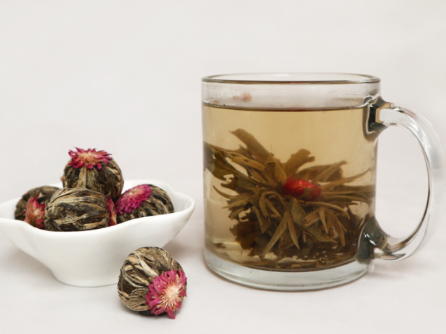 Blooming Jasmine Tea Balls in a small dish and blooming in a glass mug