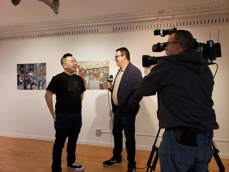 Artist Jerry Ma speaks with NY1 reporter Roger Clark in Pearl River's art gallery
