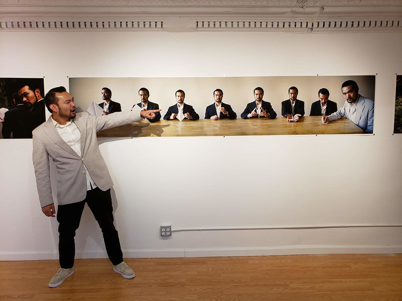 Photographer Johnny Tang pointing at his own photograph in the Pearl River Mart gallery in Tribeca