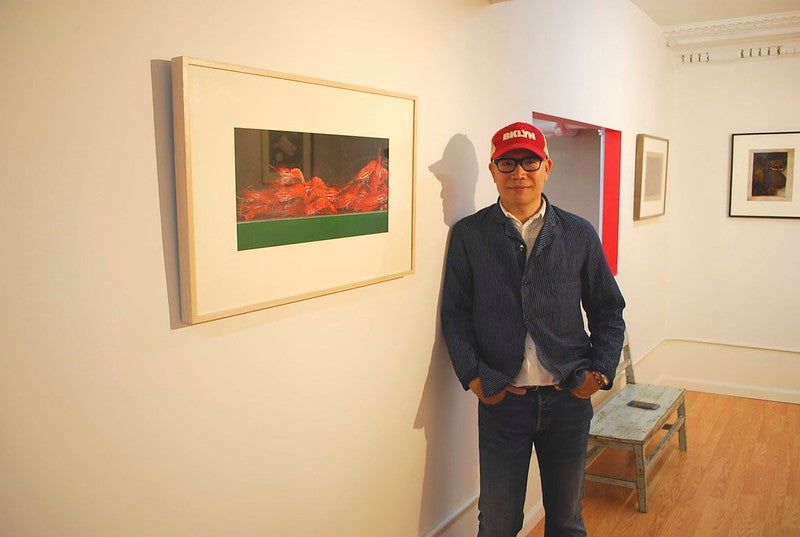 Artist Kam Mak beside one of his paintings in his exhibition in the Pearl River Mart gallery