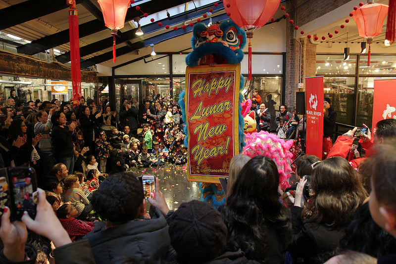 Lion dancer with happy new year banner in Chelsea Market with crowd of revelers