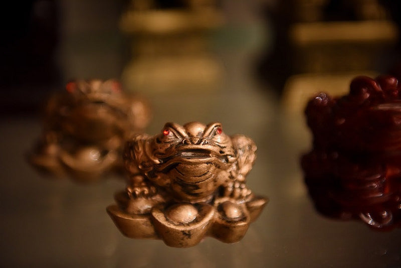 A gold colored money toad figurine with red eyes