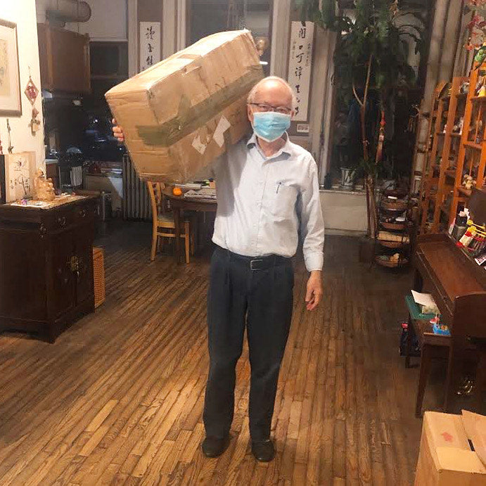 Pearl River Mart owner Mr. Chen holding larger box of masks in his NYC apartment